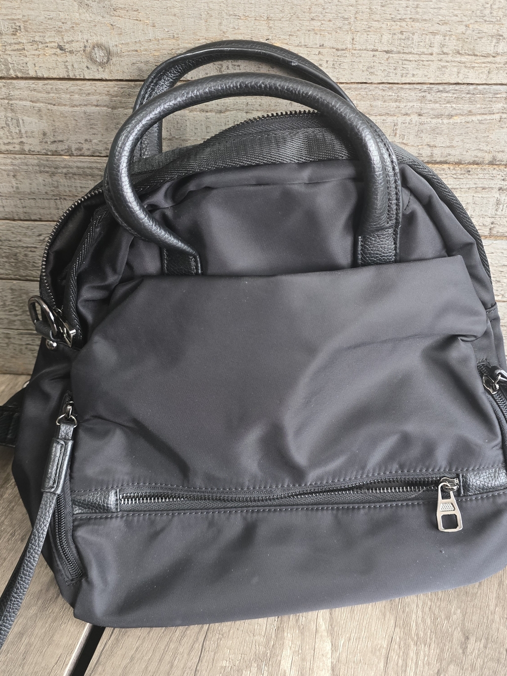 A black nylon convertible backpack purse with dual top carry handles and a front